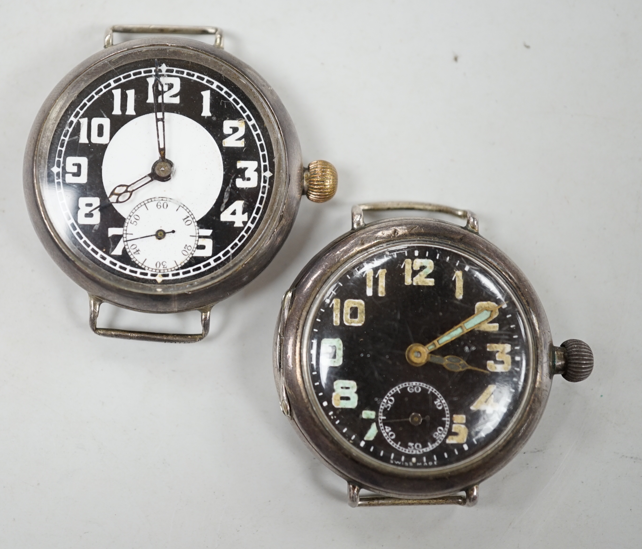 Two early 20th century silver manual wind wrist watches including black dial, both with subsidiary seconds, no straps.